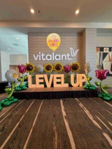 oversized foil balloon flowers with marquee letters at a corporat event