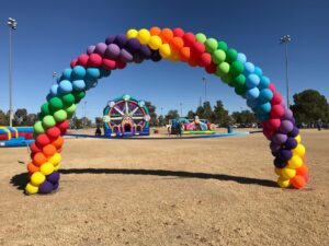 spiral rainbow Balloon Arches marks the entrance of a company picnic