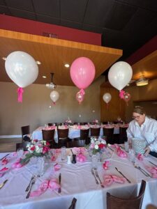 helium filled Balloons with bow accents at the neck float above banquet tables